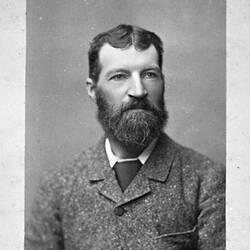 Bearded man wearing a jacket with the button done up.