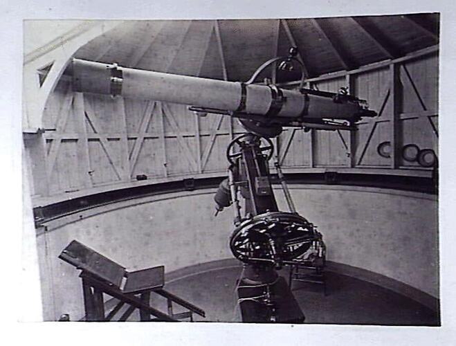 Telescope and astronomer's chair inside revolving dome.